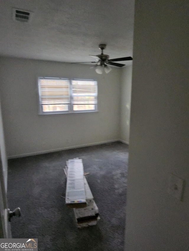 unfurnished room with dark carpet and ceiling fan