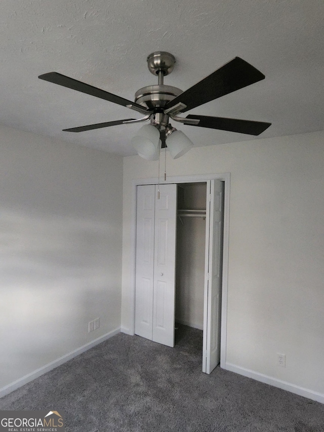 unfurnished bedroom featuring ceiling fan, a closet, and dark carpet