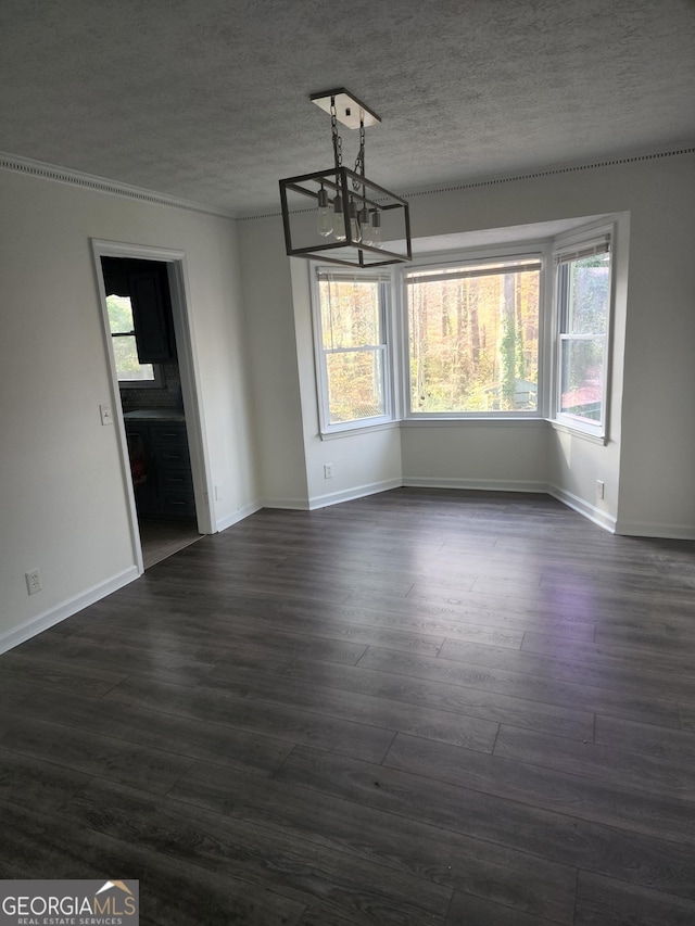 unfurnished dining area with a textured ceiling, a healthy amount of sunlight, dark hardwood / wood-style floors, and a notable chandelier