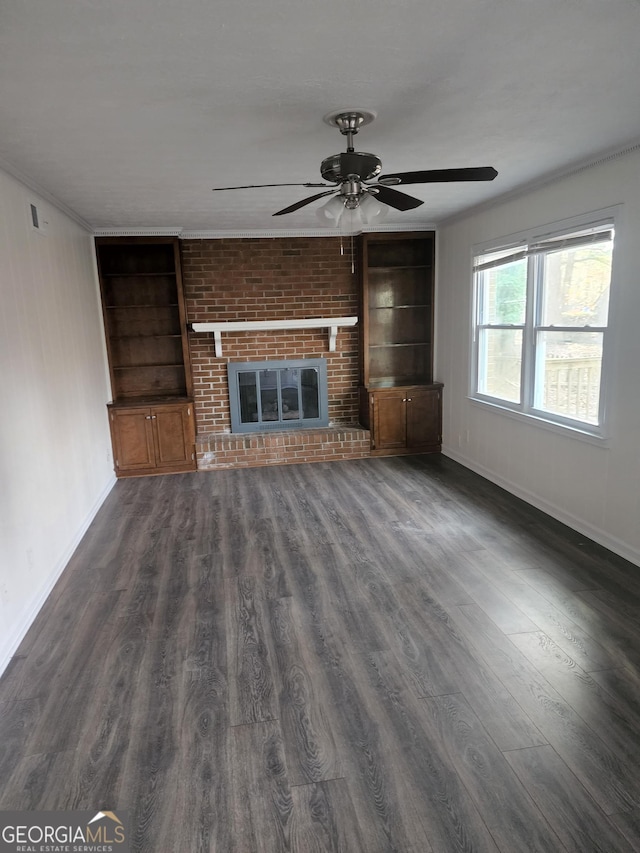 unfurnished living room featuring built in shelves, ceiling fan, a fireplace, and dark wood-type flooring