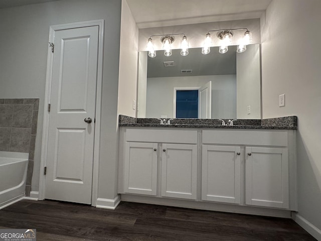 bathroom featuring vanity, hardwood / wood-style flooring, and a tub