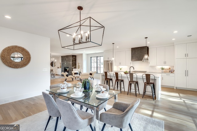 dining space with sink, a high end fireplace, and light hardwood / wood-style floors