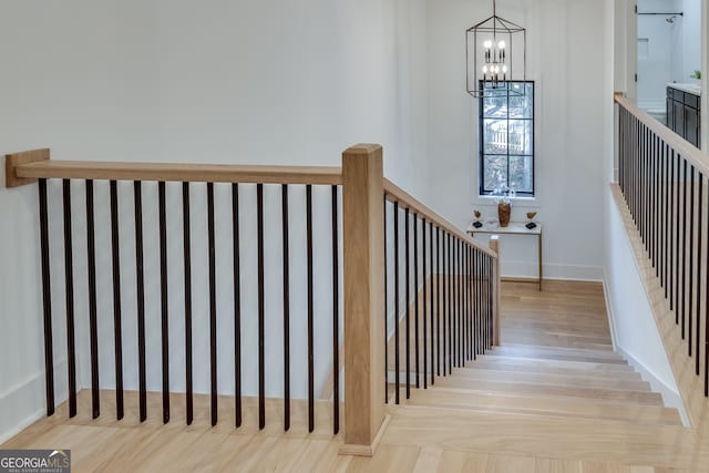 stairs featuring hardwood / wood-style flooring and a notable chandelier