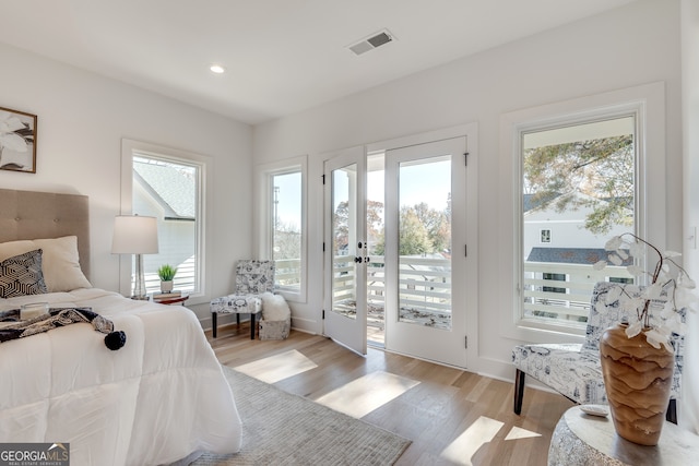 bedroom featuring access to exterior, light hardwood / wood-style flooring, and multiple windows