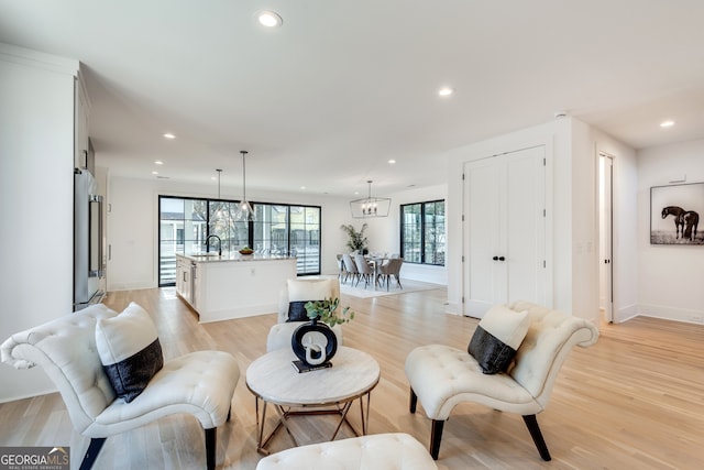 living room with light hardwood / wood-style flooring, a notable chandelier, and sink