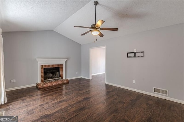 unfurnished living room with lofted ceiling, a brick fireplace, dark hardwood / wood-style floors, ceiling fan, and a textured ceiling