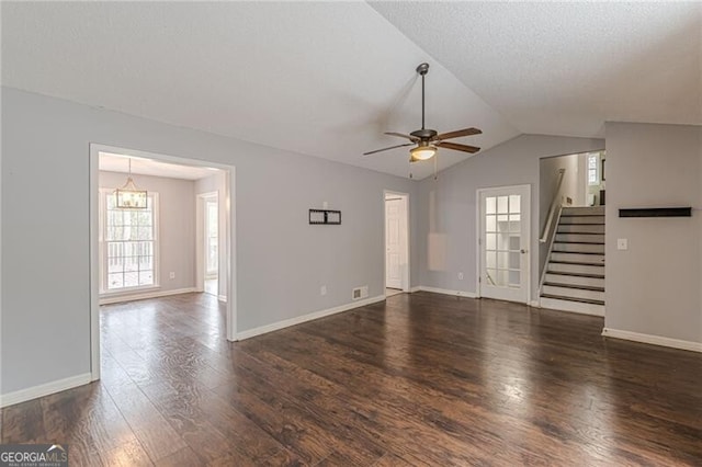 unfurnished living room with a textured ceiling, ceiling fan with notable chandelier, dark hardwood / wood-style floors, and vaulted ceiling