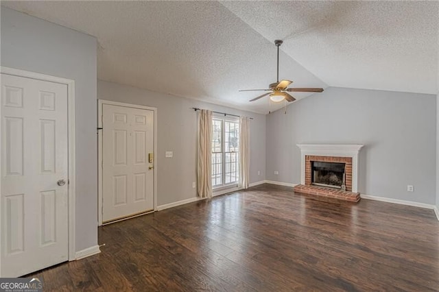 unfurnished living room with ceiling fan, dark wood-type flooring, a brick fireplace, a textured ceiling, and vaulted ceiling