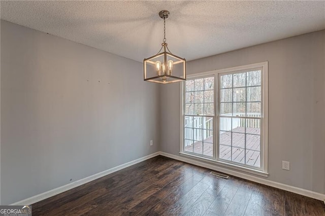 unfurnished room featuring a textured ceiling, dark wood-type flooring, and a chandelier