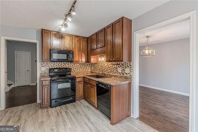 kitchen featuring backsplash, a textured ceiling, sink, black appliances, and light hardwood / wood-style floors