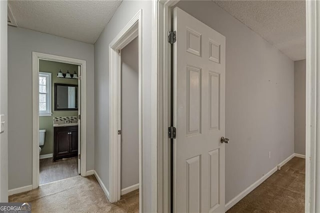 hall with light carpet and a textured ceiling