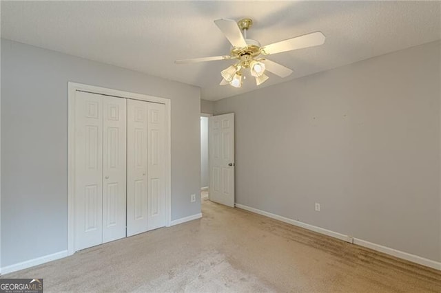 unfurnished bedroom with ceiling fan, light carpet, and a closet