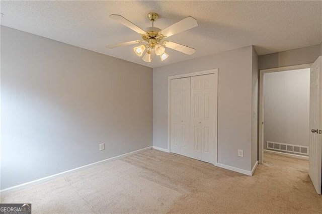 unfurnished bedroom featuring a textured ceiling, ceiling fan, light carpet, and a closet