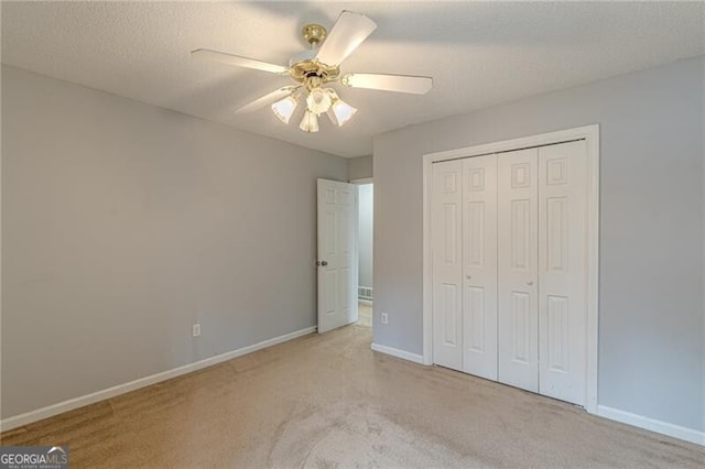 unfurnished bedroom with a textured ceiling, a closet, ceiling fan, and light colored carpet