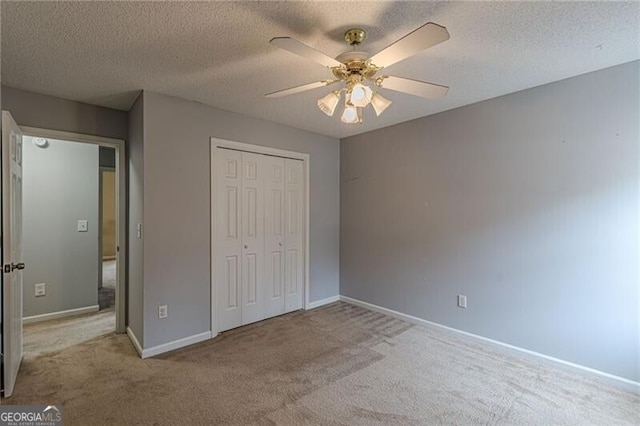 unfurnished bedroom with a textured ceiling, a closet, ceiling fan, and light colored carpet