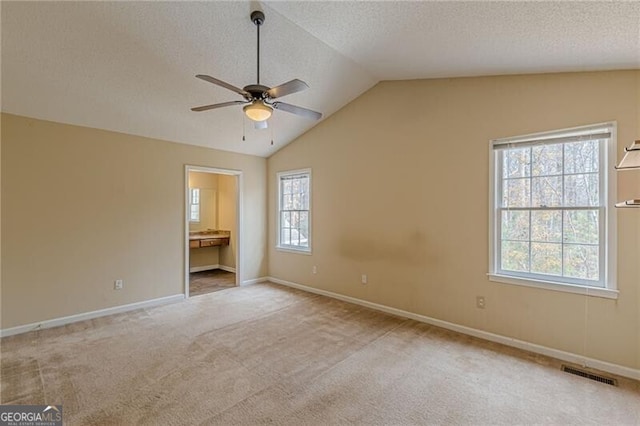 unfurnished room featuring a textured ceiling, light colored carpet, ceiling fan, and lofted ceiling