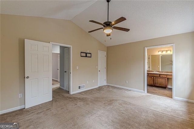 unfurnished bedroom featuring connected bathroom, ceiling fan, light carpet, and lofted ceiling