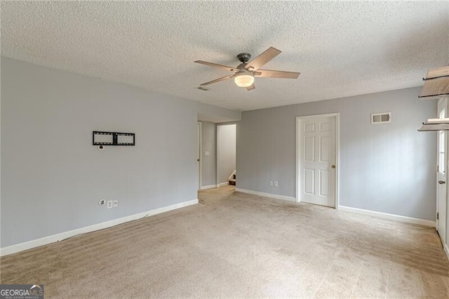 spare room with a textured ceiling, ceiling fan, and light carpet