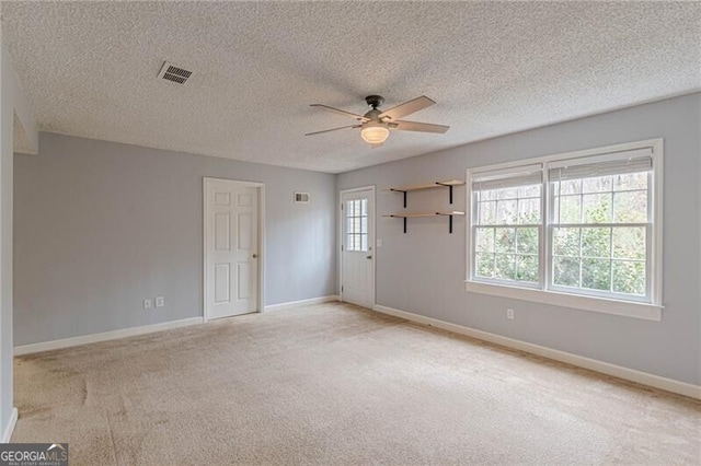 carpeted spare room featuring a textured ceiling and ceiling fan