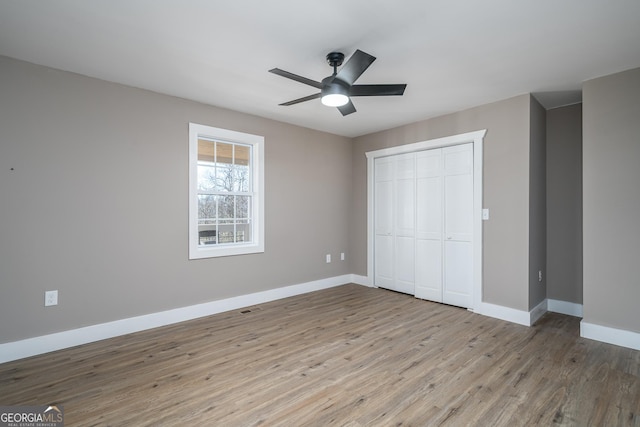unfurnished bedroom featuring a closet, visible vents, baseboards, ceiling fan, and wood finished floors