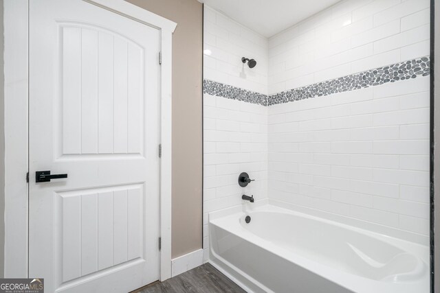 bathroom featuring baseboards,  shower combination, and wood finished floors
