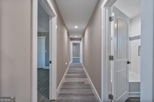 hall featuring dark wood-type flooring, baseboards, and recessed lighting