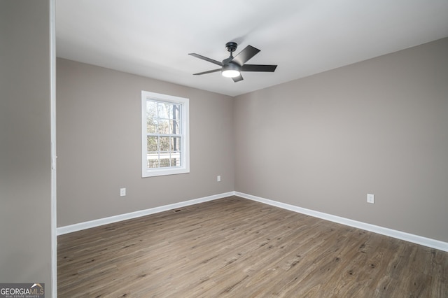 unfurnished room featuring a ceiling fan, baseboards, and wood finished floors