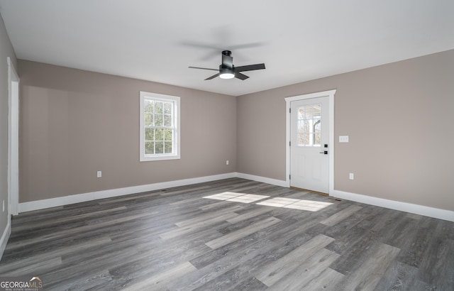 empty room with baseboards, a ceiling fan, and dark wood finished floors