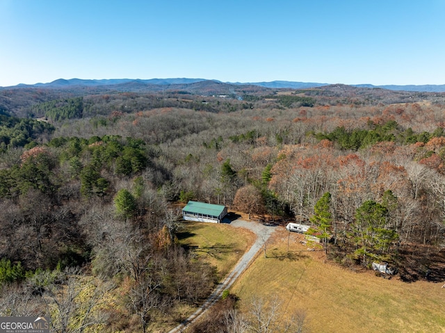 drone / aerial view featuring a wooded view and a mountain view