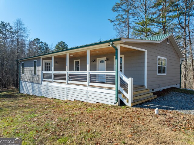 view of front of house featuring covered porch, metal roof, crawl space, and a front yard