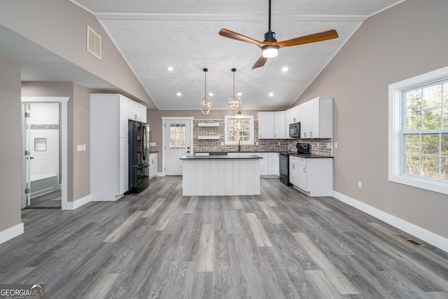 kitchen with white cabinetry, hanging light fixtures, a kitchen island, black appliances, and light wood-type flooring