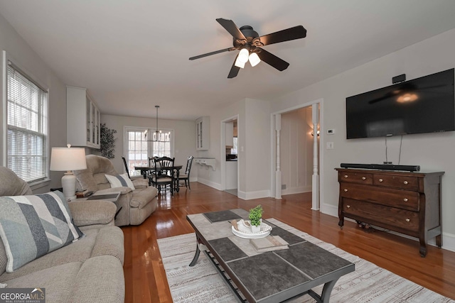 living room with ceiling fan with notable chandelier and wood-type flooring