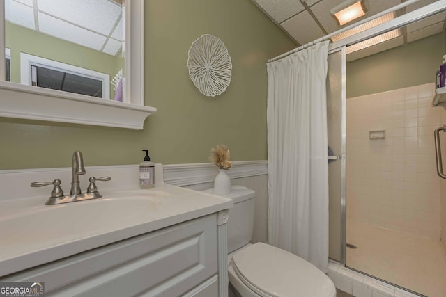 bathroom with a shower with curtain, vanity, toilet, and a drop ceiling