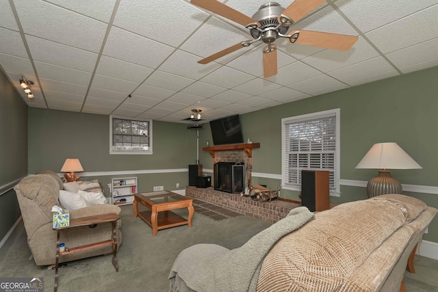 carpeted living room featuring a paneled ceiling, a brick fireplace, and ceiling fan