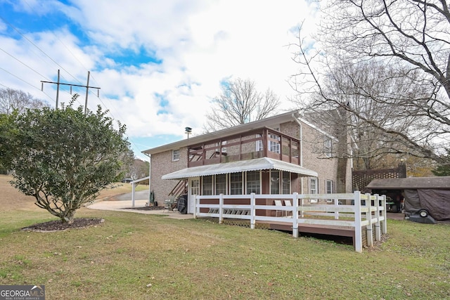 back of property featuring a yard, a balcony, a wooden deck, and a sunroom