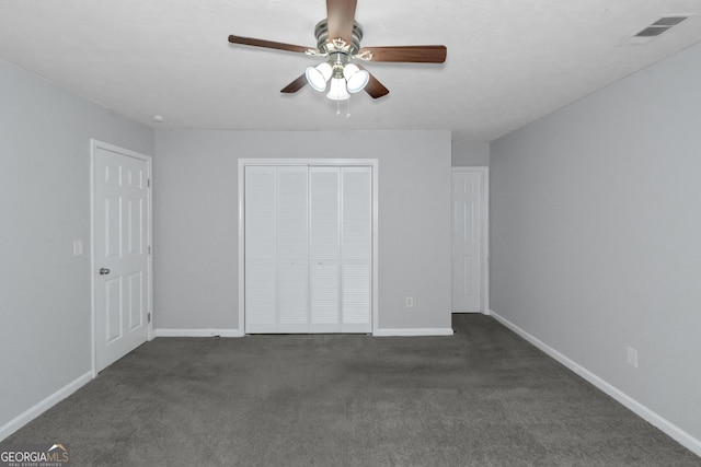 unfurnished bedroom with ceiling fan, dark carpet, and a closet