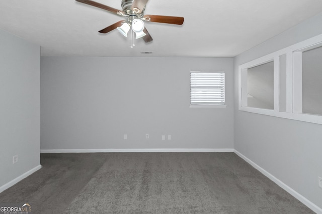 spare room featuring ceiling fan and dark carpet