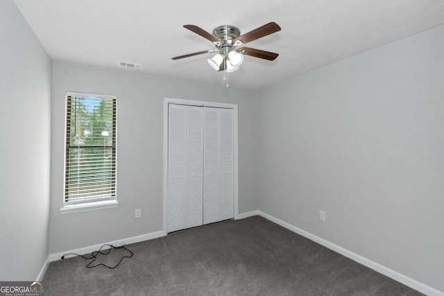 unfurnished bedroom featuring dark colored carpet, ceiling fan, and a closet