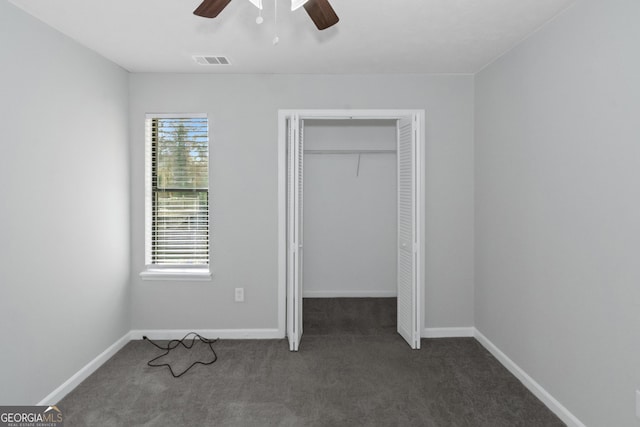 unfurnished bedroom featuring ceiling fan, dark carpet, and a closet