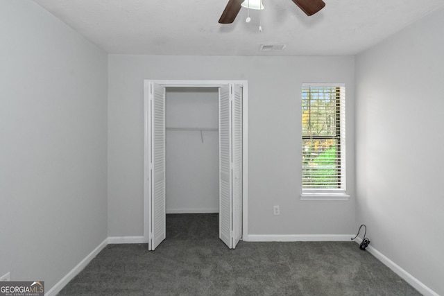 unfurnished bedroom with ceiling fan and dark carpet