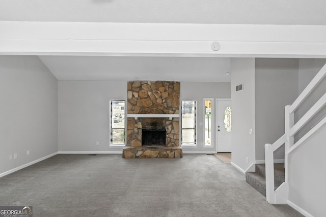 unfurnished living room featuring carpet flooring, vaulted ceiling, and a stone fireplace