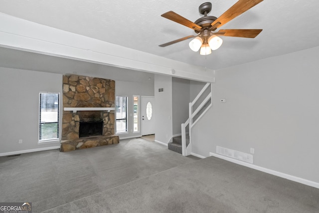 unfurnished living room with carpet, ceiling fan, and a stone fireplace