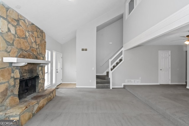 unfurnished living room with carpet flooring, a stone fireplace, ceiling fan, and high vaulted ceiling