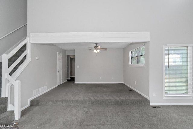 unfurnished living room featuring dark colored carpet and ceiling fan