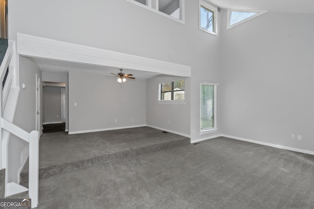 unfurnished living room featuring ceiling fan, a high ceiling, and dark colored carpet