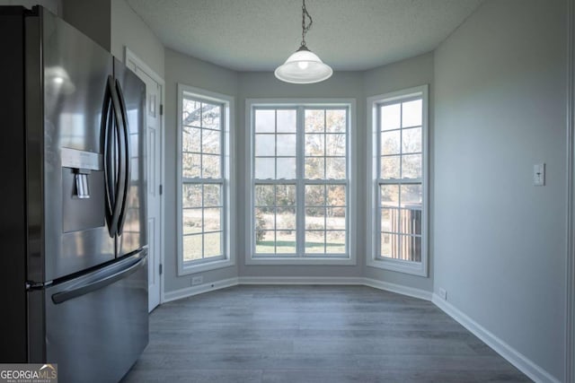 unfurnished dining area featuring dark hardwood / wood-style flooring and a textured ceiling