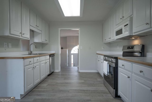 kitchen featuring sink, white cabinets, light hardwood / wood-style floors, and appliances with stainless steel finishes