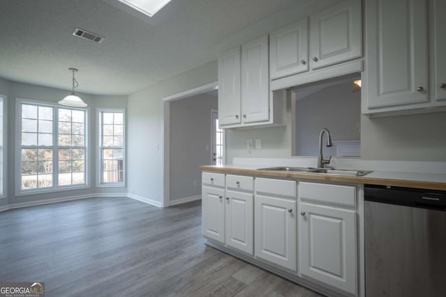 kitchen featuring pendant lighting, dishwasher, white cabinets, sink, and light wood-type flooring