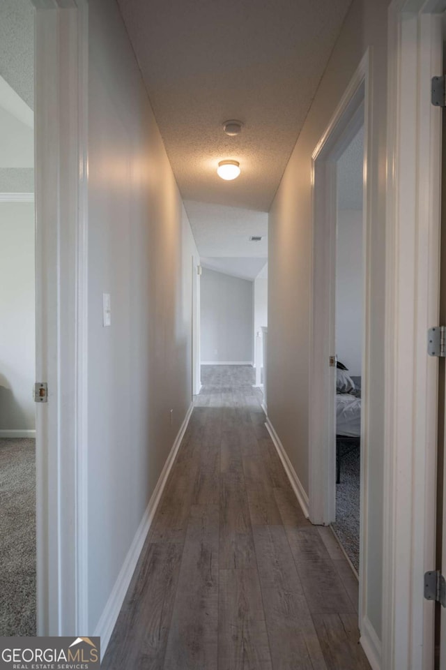 hall with a textured ceiling and dark hardwood / wood-style floors