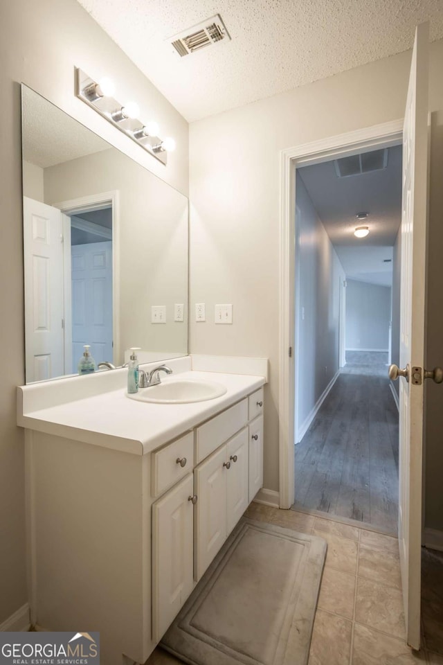 bathroom featuring a textured ceiling, vanity, and hardwood / wood-style flooring